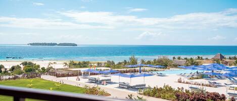 Un resort con zona de piscina, sillas de descanso y vistas al océano.