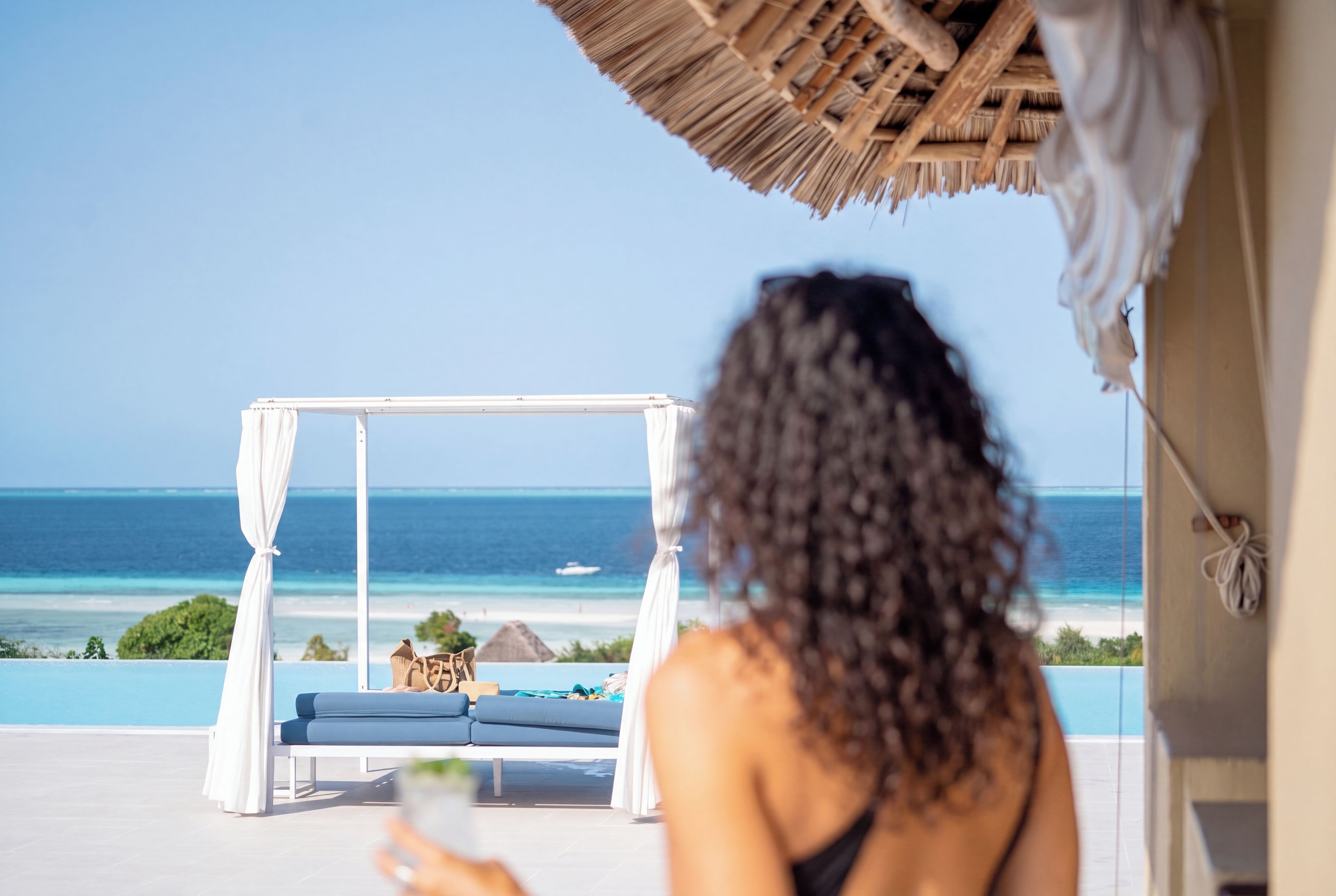Une personne assise sur un balcon, avec vue sur l’océan et une plage.