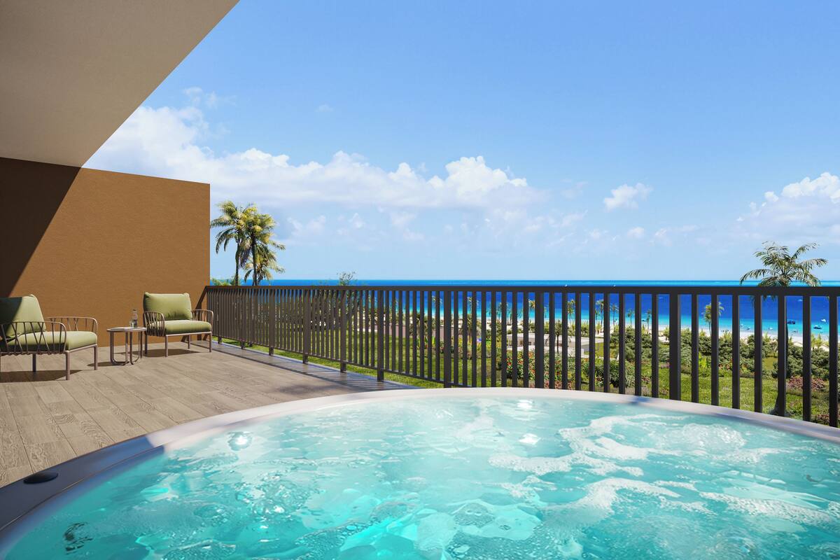 Un jacuzzi con vista al océano, una terraza de madera y sillas de descanso.
