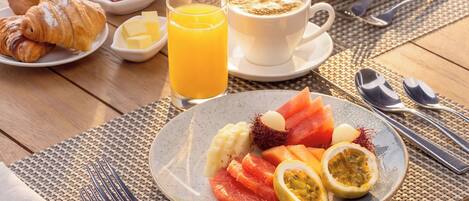 A breakfast table with croissants, fruit, coffee, and juice.