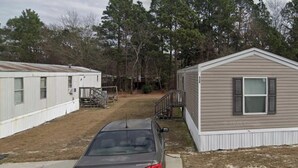 A mobile home with a car parked in front, a small shed, and a grassy yard. - Beautiful home waiting for you (Cumberland County)