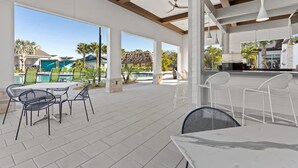 An outdoor patio area with tables and chairs, a pool in the background, and a clear view of the surrounding landscape. - Beautiful Decor 2BR Apartment Near Disney (Kissimmee)