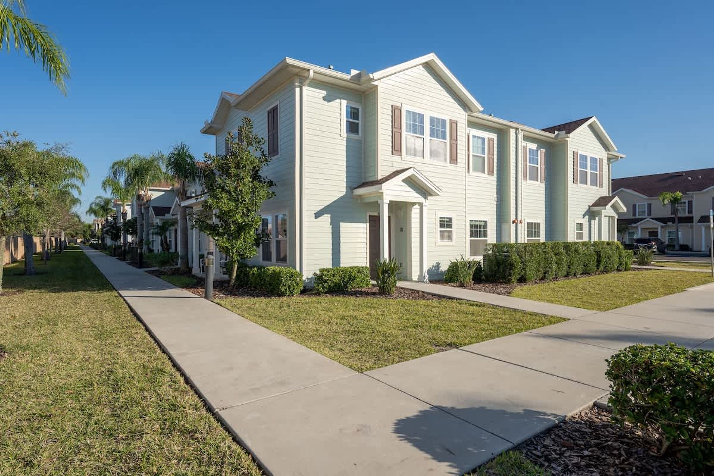 A two-story residential building with a symmetrical facade, a front porch, and a well-maintained lawn.