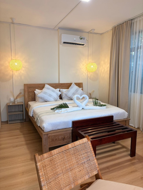 A neatly arranged bedroom with a bed, bedside tables, a wooden bench, and a woven chair. - Seafront Sunset Suite, Le Morne Retreat & Terrace (La Gaulette)
