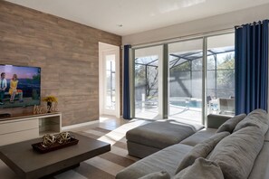 En moderne stue med et stort fladskærms-tv, en sofa og et sofabord.