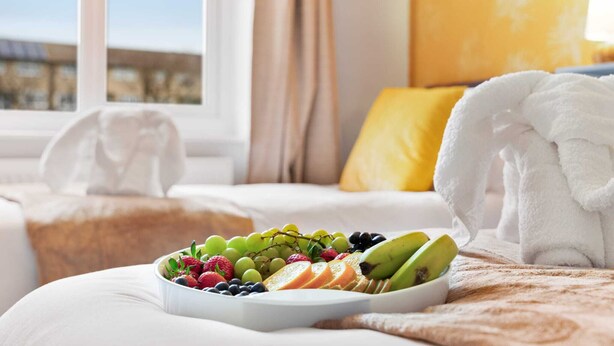 Et hotelværelse med en seng, en frugtskål og et vindue med udsigt.