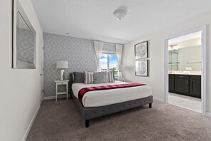 Un dormitorio con cama, mesitas de noche, una ventana con cortinas, un espejo y vistas al baño.