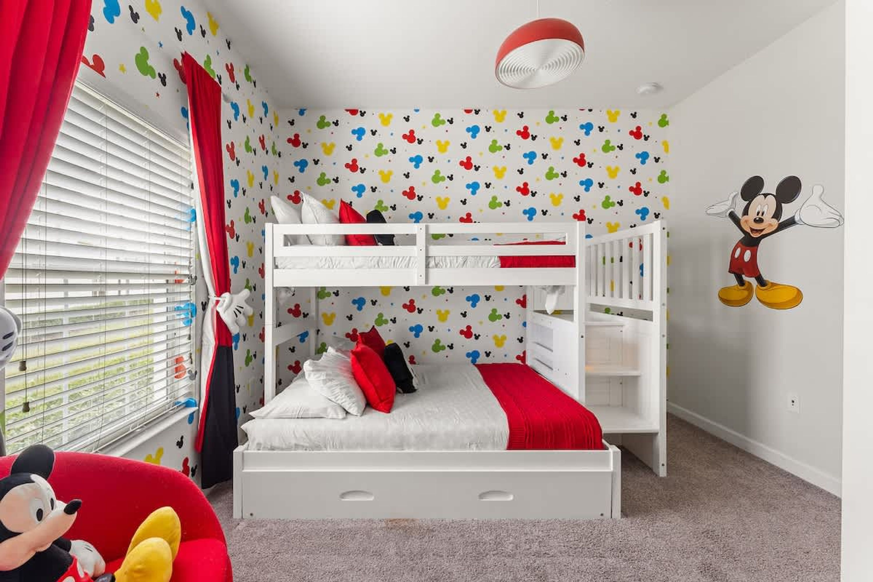 A child's bedroom with a bunk bed, colorful wall decals, and a Mickey Mouse mural.