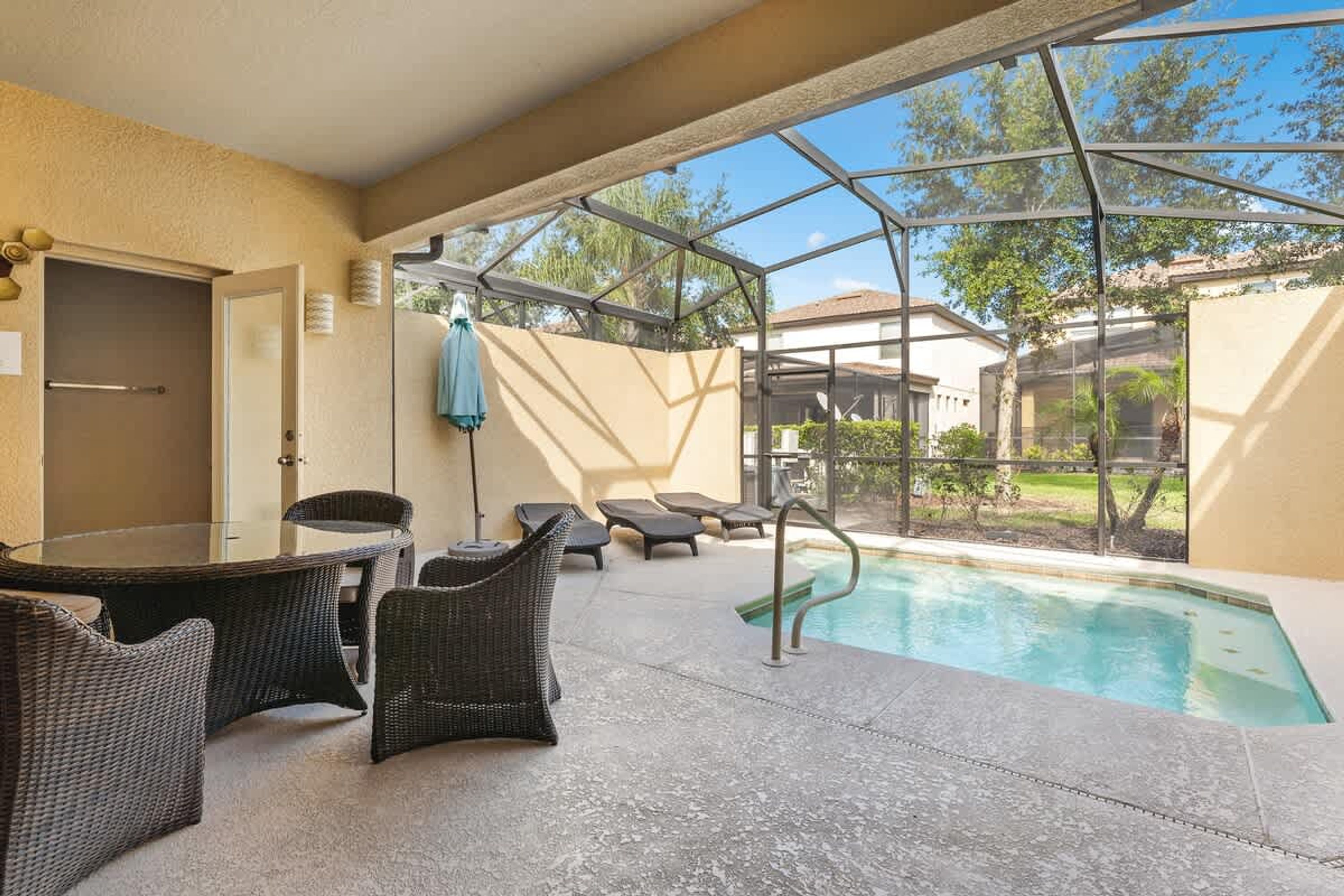 Un espace extérieur abrité comprenant une piscine, des chaises longues et une table avec des chaises.