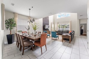 A spacious living area with a dining table, chairs, a sofa, and a TV. - 5BR Themed Bedrooms at Storey Lake (Kissimmee)