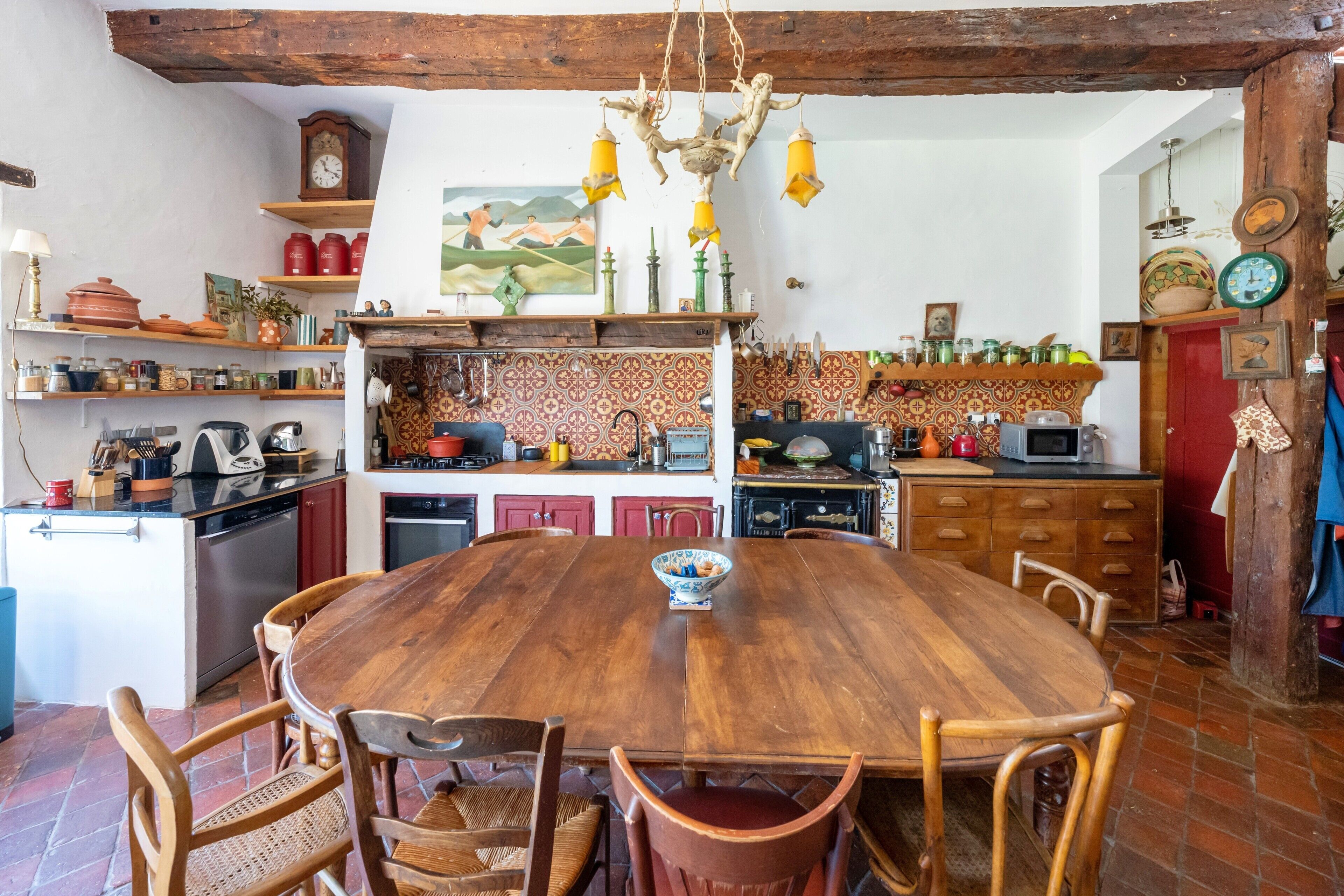 Une cuisine rustique avec une table en bois, des chaises et divers appareils de cuisine.
