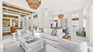 Una sala de estar amplia con un sofá blanco, una mesa de centro y un comedor con una cocina al fondo.