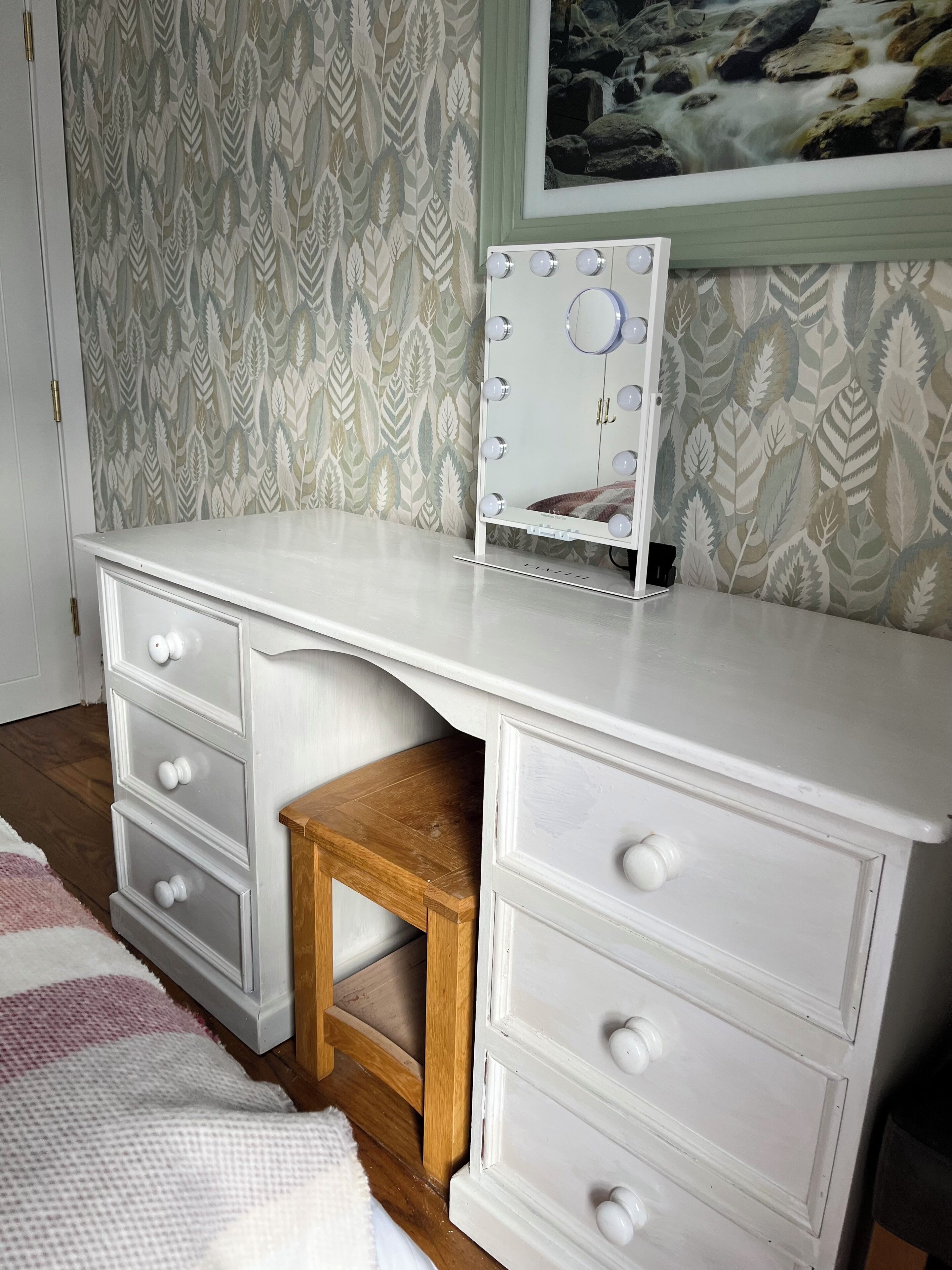 A white dresser with multiple drawers and a mirror with lights.