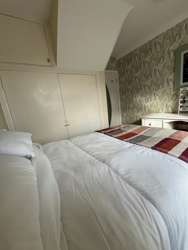 A bedroom with a bed, a wardrobe, a dresser, and a mirror.