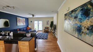 A modern kitchen with a dishwasher, a dining area with a patterned rug, and a large abstract painting on the wall. - Adorable 2-bedroom townhome with in Vibrant Atlanta - walk to the stadiums (Atlanta)