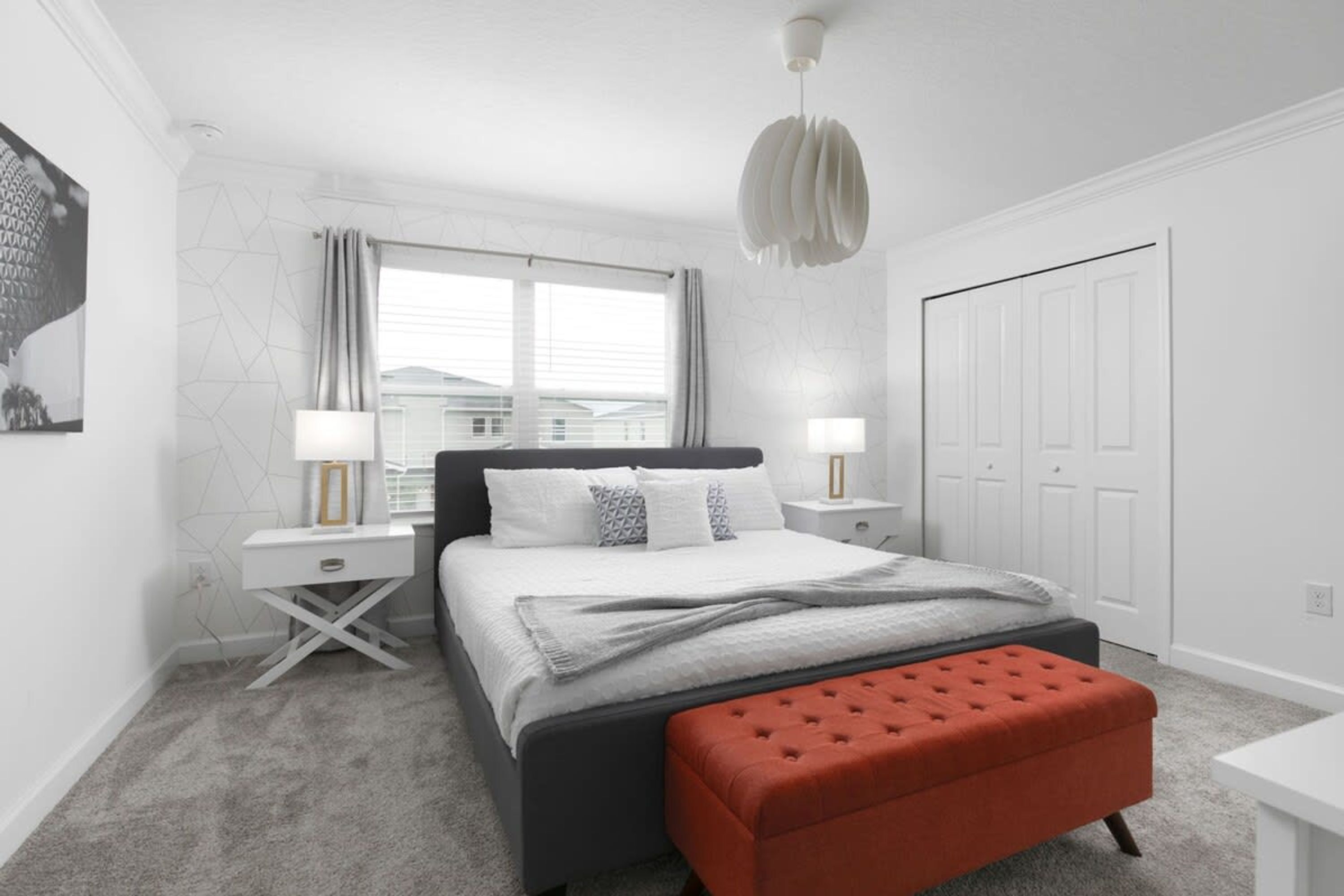 Un dormitorio moderno con cama, mesitas de noche, ventana y puerta.