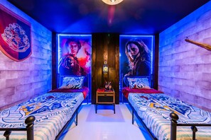 A room with two beds, a small table, and a wall with a crest emblem. - Themed 9BR Retreat, Pool & Soccer Fun (Kissimmee)