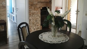 A dining area with a round table, chairs, a vase with flowers, a fireplace, and a stone wall. - 3-room 95sqm holiday apartment Casa Antico 2 (Steinheim an der Murr)