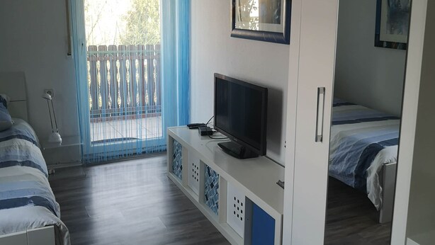 A bedroom with a TV, a bed, a wardrobe, and a balcony. - 3-room 95sqm holiday apartment Casa Antico 2 (Steinheim an der Murr)
