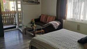 A bedroom with a bed, a sofa, a small table with a vase, and a window with curtains. - 3-room 95sqm holiday apartment Casa Antico 2 (Steinheim an der Murr)