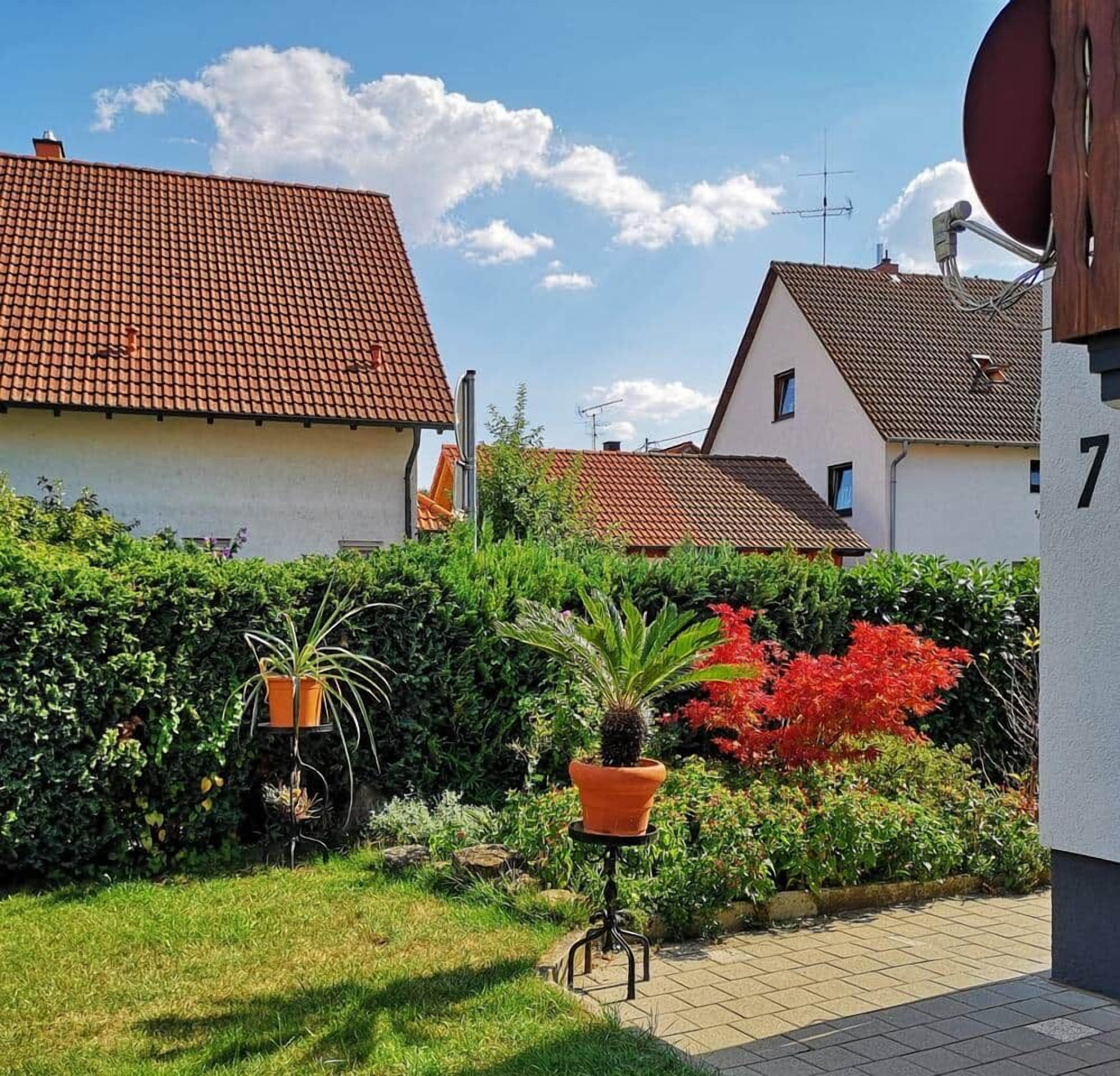 Een woonwijk met huizen, een verhard pad en potplanten.