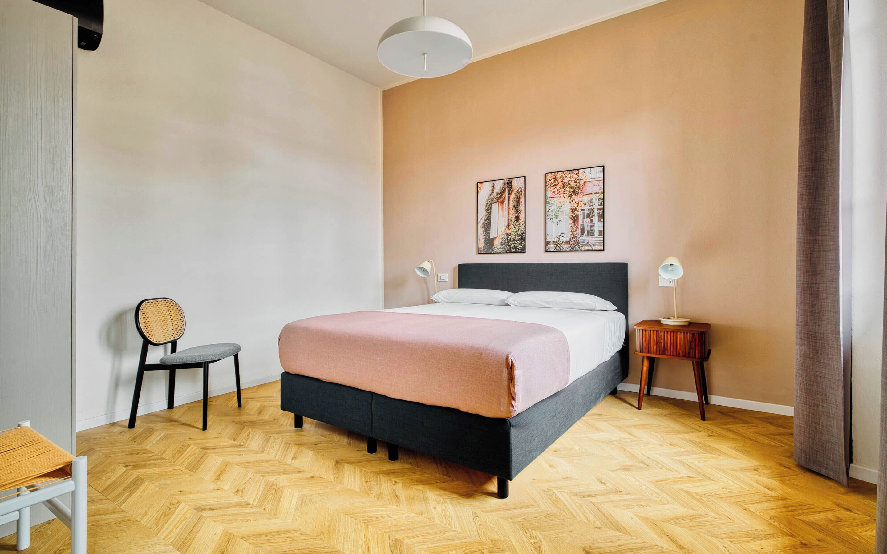 Une chambre à coucher comprenant un lit, deux tables de chevet, une chaise et deux lampes fixées au mur.
