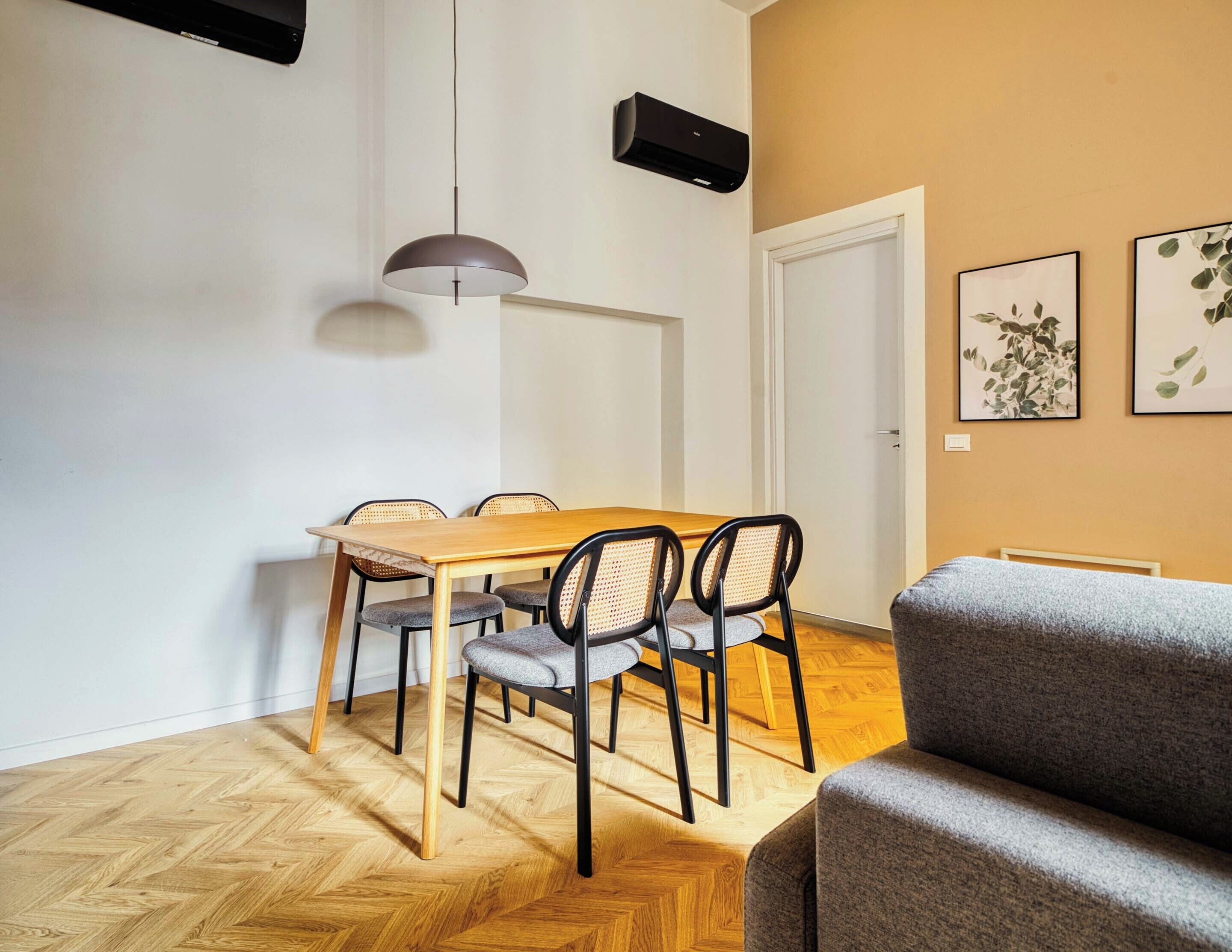 Un comedor con mesa y sillas de madera, una lámpara colgante y una puerta.
