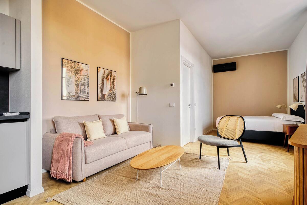 Ein modernes Hotelzimmer mit Sofa, Sessel, Bett und einem kleinen Holztisch.