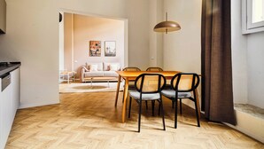 A modern living room with a sofa, a dining table with chairs, a kitchen area, and a large window with curtains. - Limehome Florence Via Guelfa (Florence)
