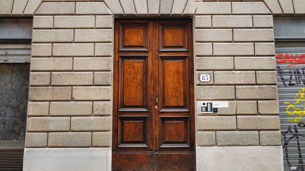 A double wooden door with a number '85' above it, set in a building with a brick facade. - Limehome Florence Via Guelfa (Florence)