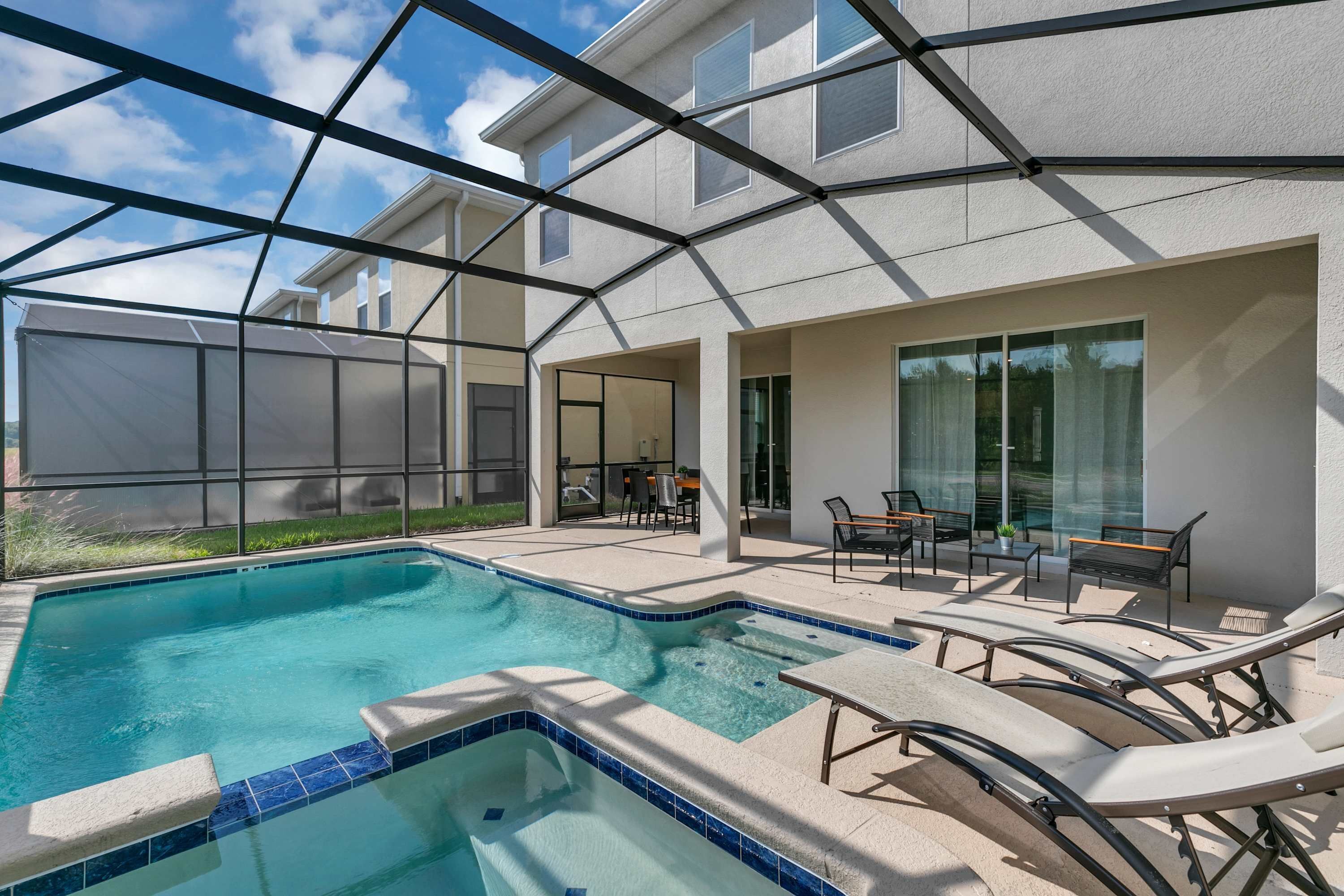 Une piscine avec des chaises longues et un espace patio couvert.