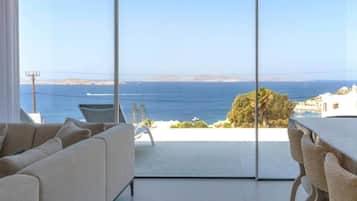 Un salon moderne doté d’une grande porte vitrée donnant sur un balcon avec vue sur la mer.