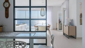 Un interior modern amb un gran finestral, una zona de menjador i vista al mar.