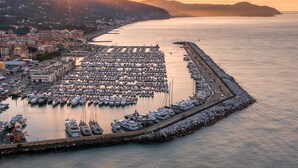 A marina with numerous boats docked, a waterfront promenade, and a cityscape in the background. - Amiado Apartment With Sea View Balcony (Lavagna)