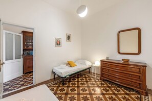 A bedroom with a bed, dresser, mirror, and a patterned floor. - Amiado Apartment With Sea View Balcony (Lavagna)