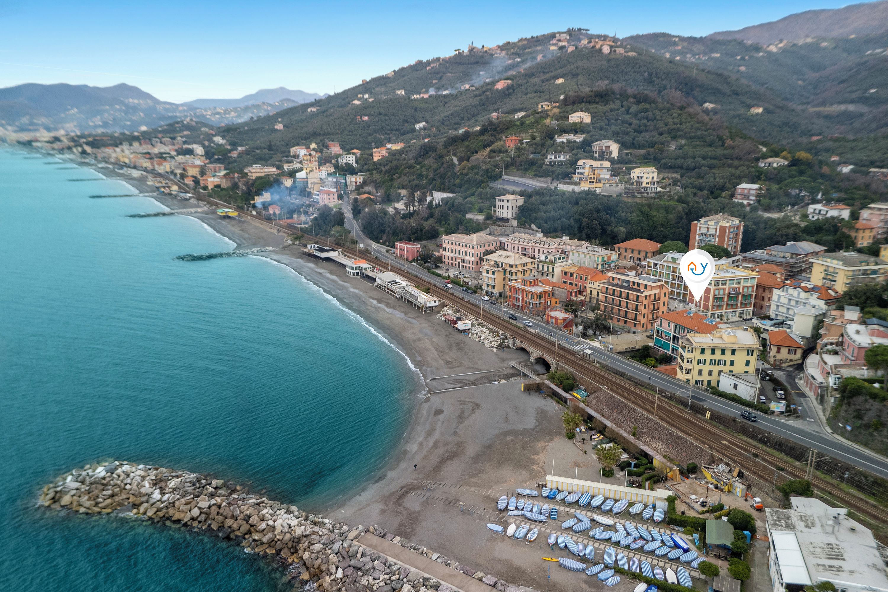 Vista aérea de una ciudad costera con playa, edificios y una línea de tren.