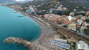 An aerial view of a coastal town with a beach, buildings, and a railway line. - Amiado Apartment With Sea View Balcony (Lavagna)