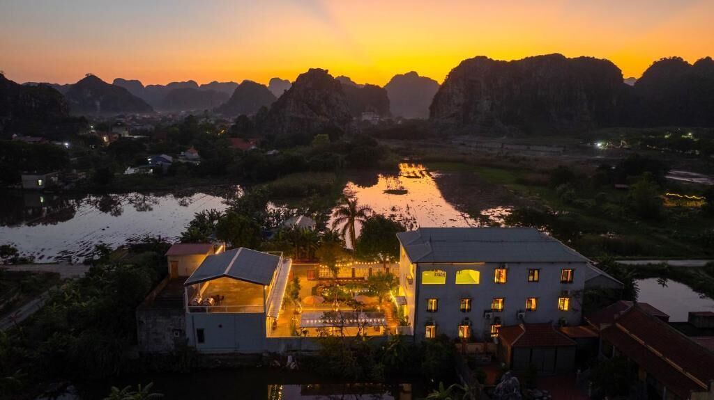 A hotel with a view of a river and mountains at sunset.