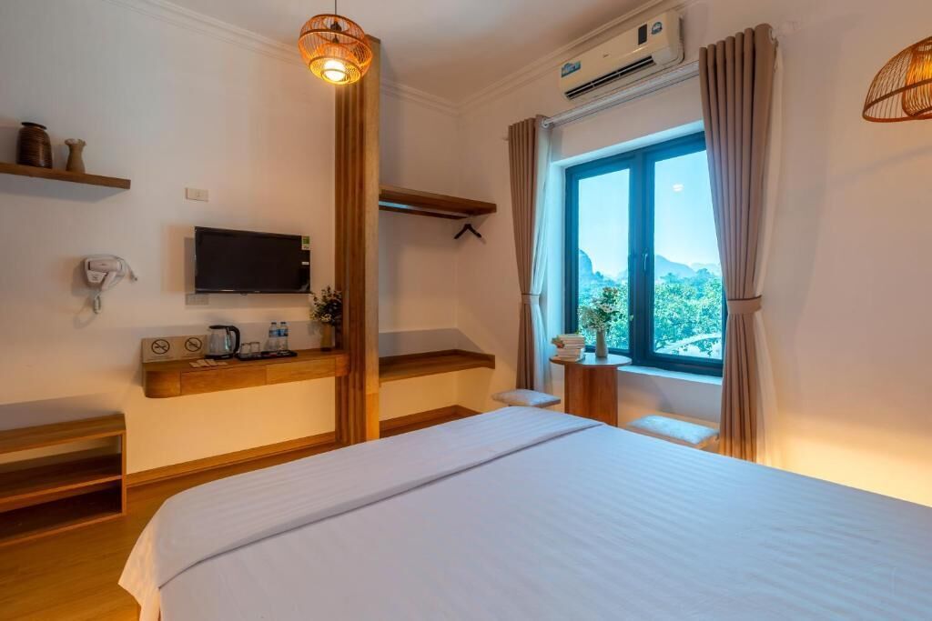 Una habitación de hotel con cama, televisión, zona de café y ventana con cortinas.