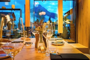 A restaurant table set with wine glasses, a vase with flowers, and a candle. - Berghotel Kleiner Biber (Warth)