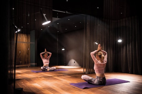 A yoga studio with wooden floors, purple mats, and a large mirror.
