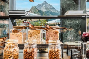 Une présentation de produits alimentaires comprenant divers pots de noix et de granola, une cuillère en bois et une pancarte indiquant « Marmelade » et « Tröcken ».