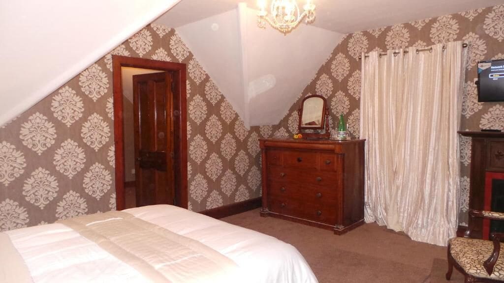 Une chambre à coucher avec un lit, une commode, un miroir et un téléviseur.
