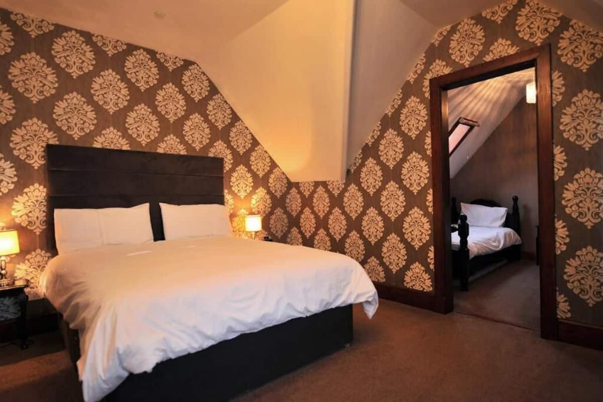A bedroom with a large bed, a nightstand, a lamp, and a mirror.