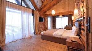 Une chambre à coucher de style chalet, avec un grand lit, un plancher en bois et un balcon.