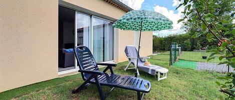 A patio with two lounge chairs, a small table, and a patterned umbrella.