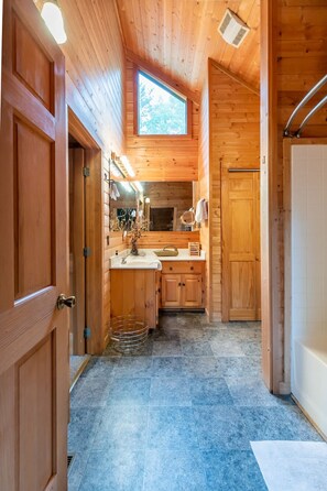 Interno di una baita in legno con angolo cottura, pareti in legno e una finestra.