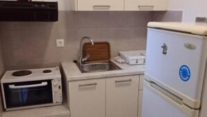 Una cocina compacta con microondas integrado, un lavamanos y un refrigerador pequeño.