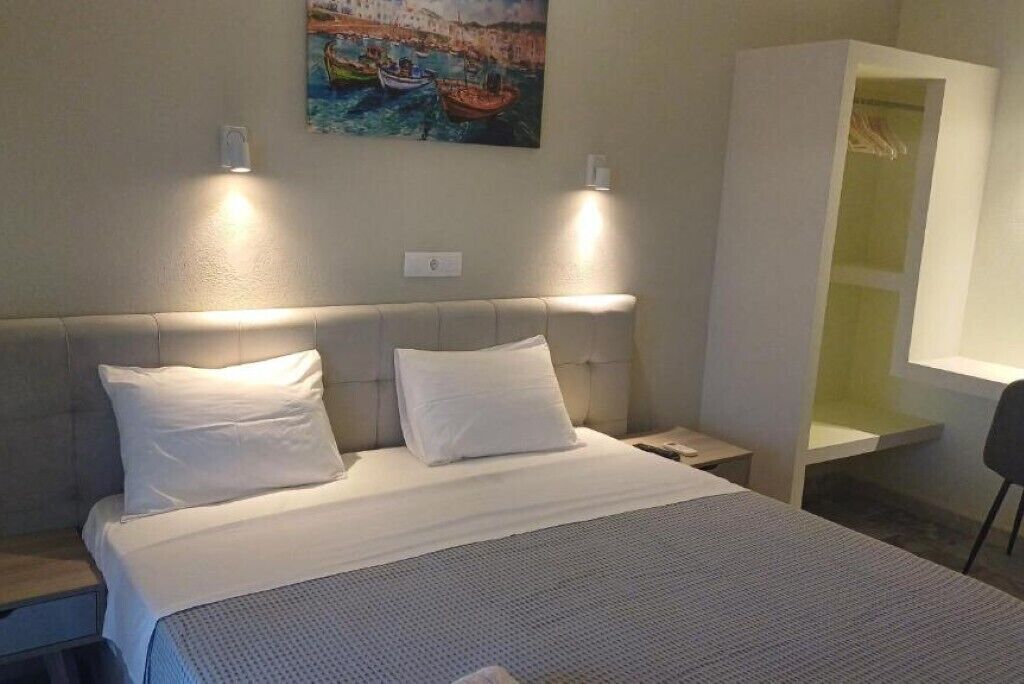 A neatly made bed with white linens, a headboard, and two bedside lamps.