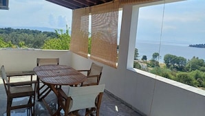 Un balcón al aire libre con una mesa y sillas, con vistas a una masa de agua y vegetación.